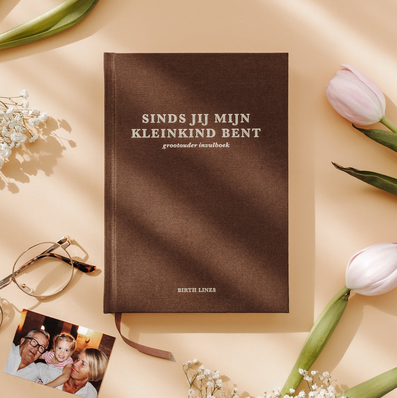 Birth Lines grootouder invulboek Sinds jij mijn kleinkind bent met bruine linnen kaft, tulpen en familiefoto op warme beige achtergrond