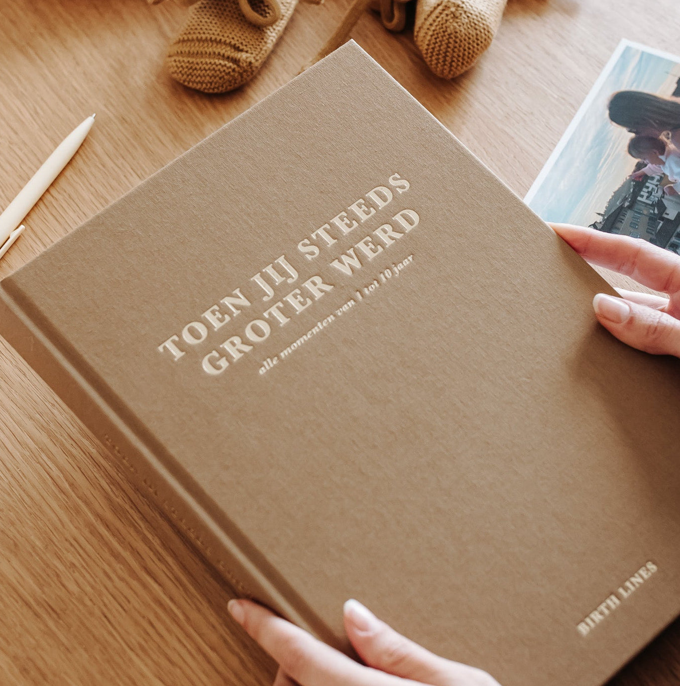 Birth Lines opgroei invulboek Toen jij steeds groter werd met linnen kaft vastgehouden op houten tafel met babyschoentjes en foto