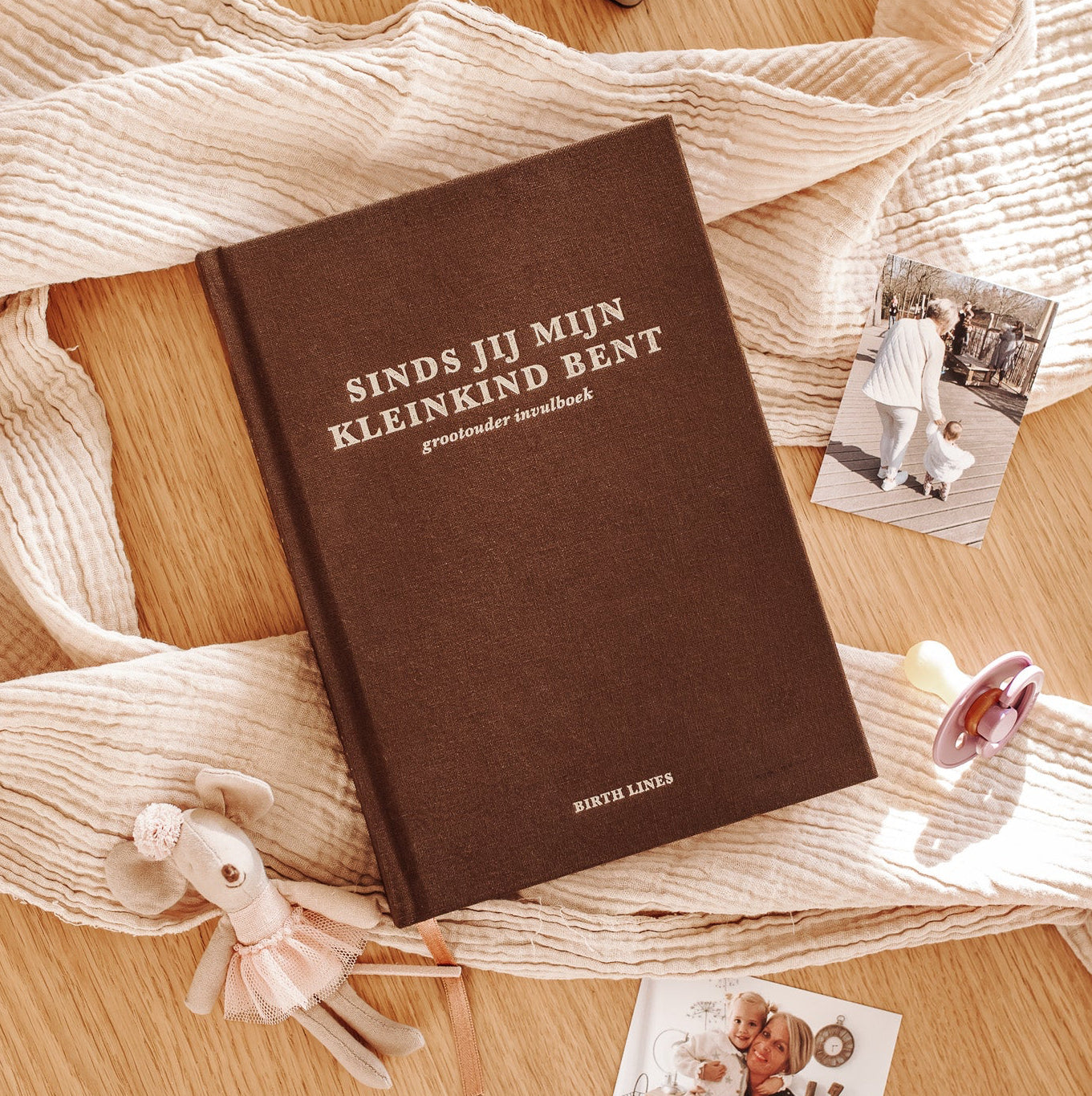 Birth Lines grootouder invulboek Sinds jij mijn kleinkind bent met linnen kaft op houten tafel met foto’s, speen en knuffel
